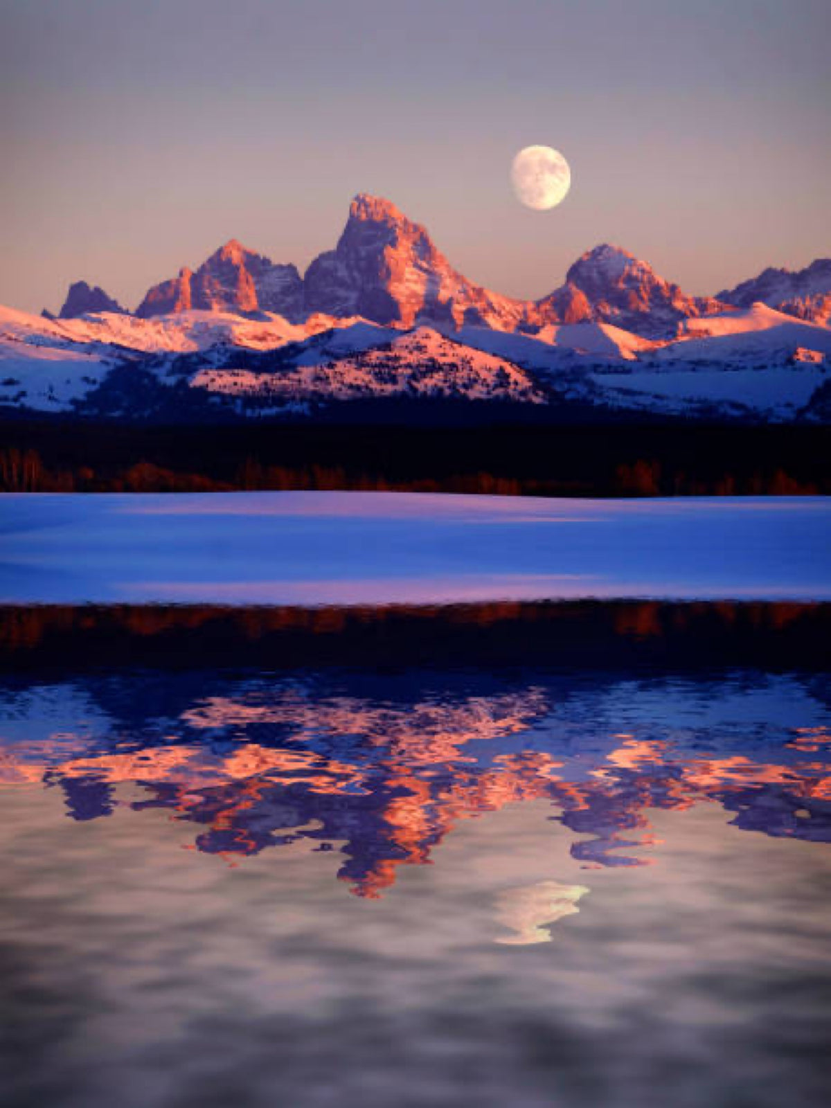 Moon rising over the Tetons reflected in still water